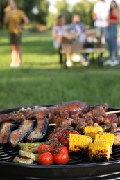 Group of friends having party outdoors, focus on barbecue grill with food