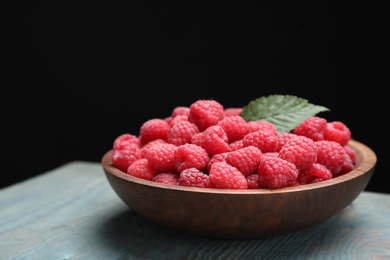 Photo of Delicious fresh ripe raspberries in plate on blue wooden table