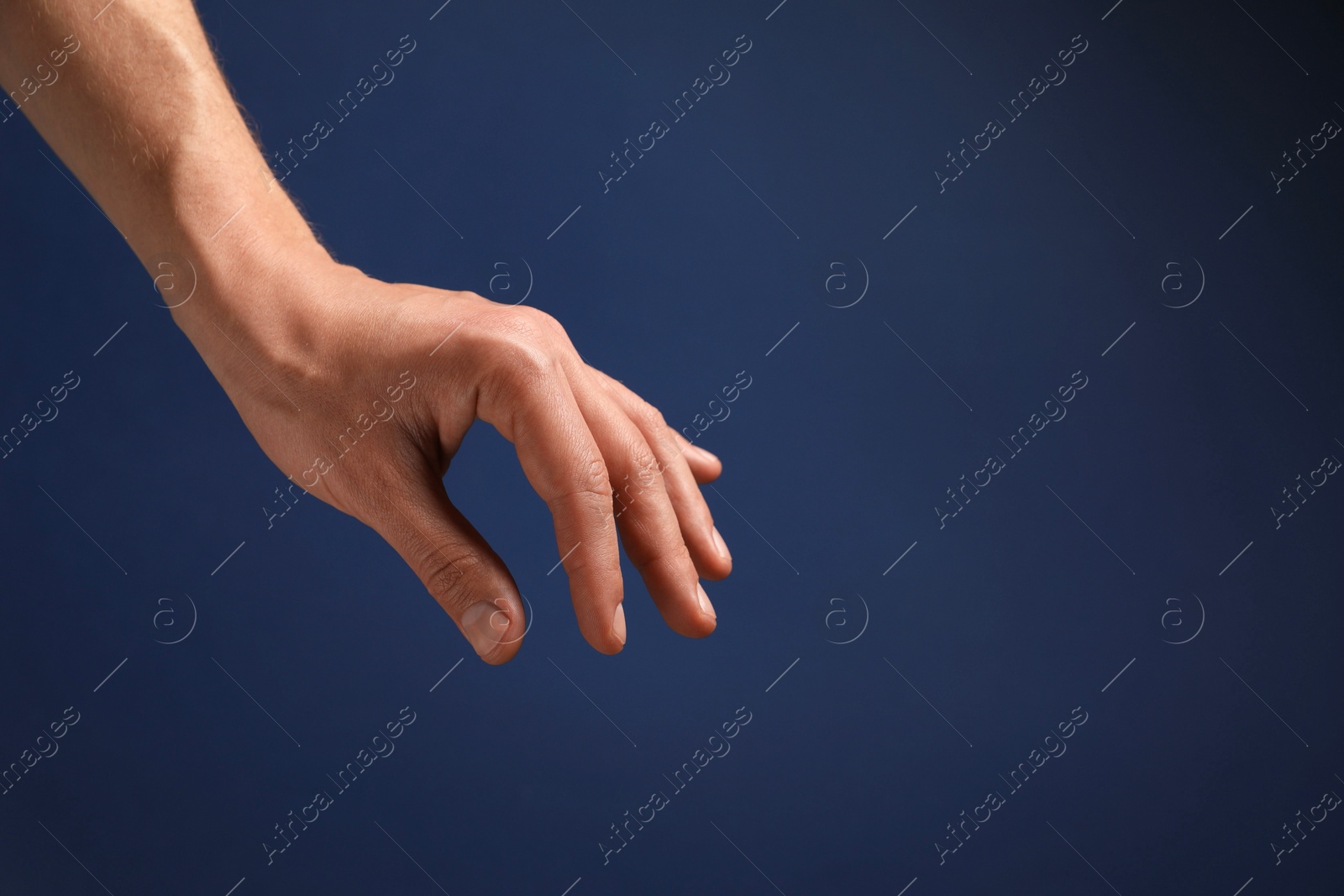 Photo of Man holding something in hand on blue background, closeup. Space for text