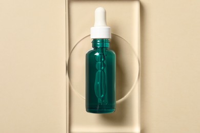 Photo of Bottle of cosmetic serum on beige background, top view