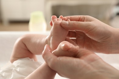 Photo of Mother massaging her cute baby with oil indoors, closeup