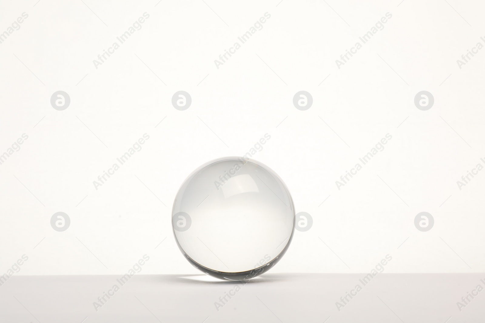 Photo of Transparent glass ball on white background. Space for text