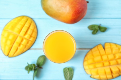 Glass with fresh mango juice and tasty fruits on wooden table, flat lay