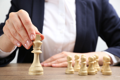 Photo of Woman with chess piece at wooden table, closeup. Career promotion concept
