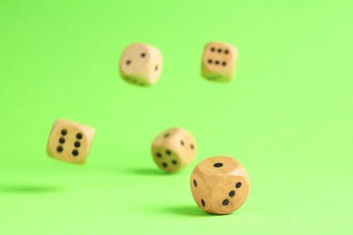 Many wooden game dices falling on green background. Space for text