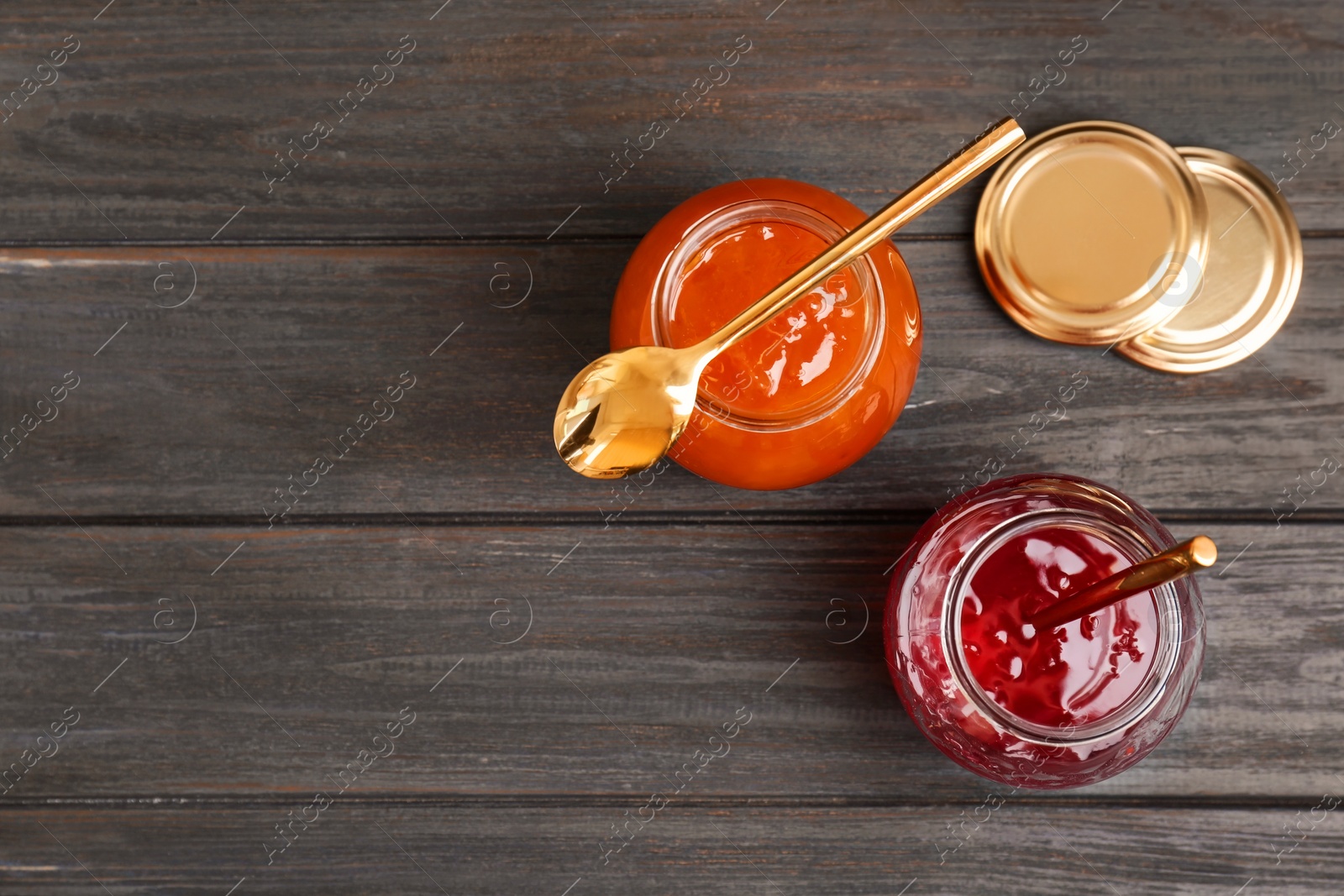 Photo of Jars with tasty sweet jam on wooden table