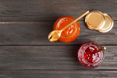 Photo of Jars with tasty sweet jam on wooden table