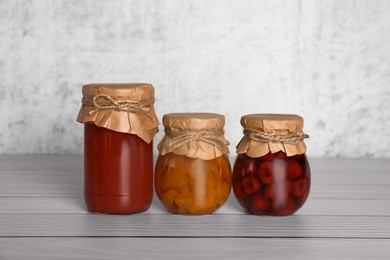 Jars with canned fruit jams on wooden table