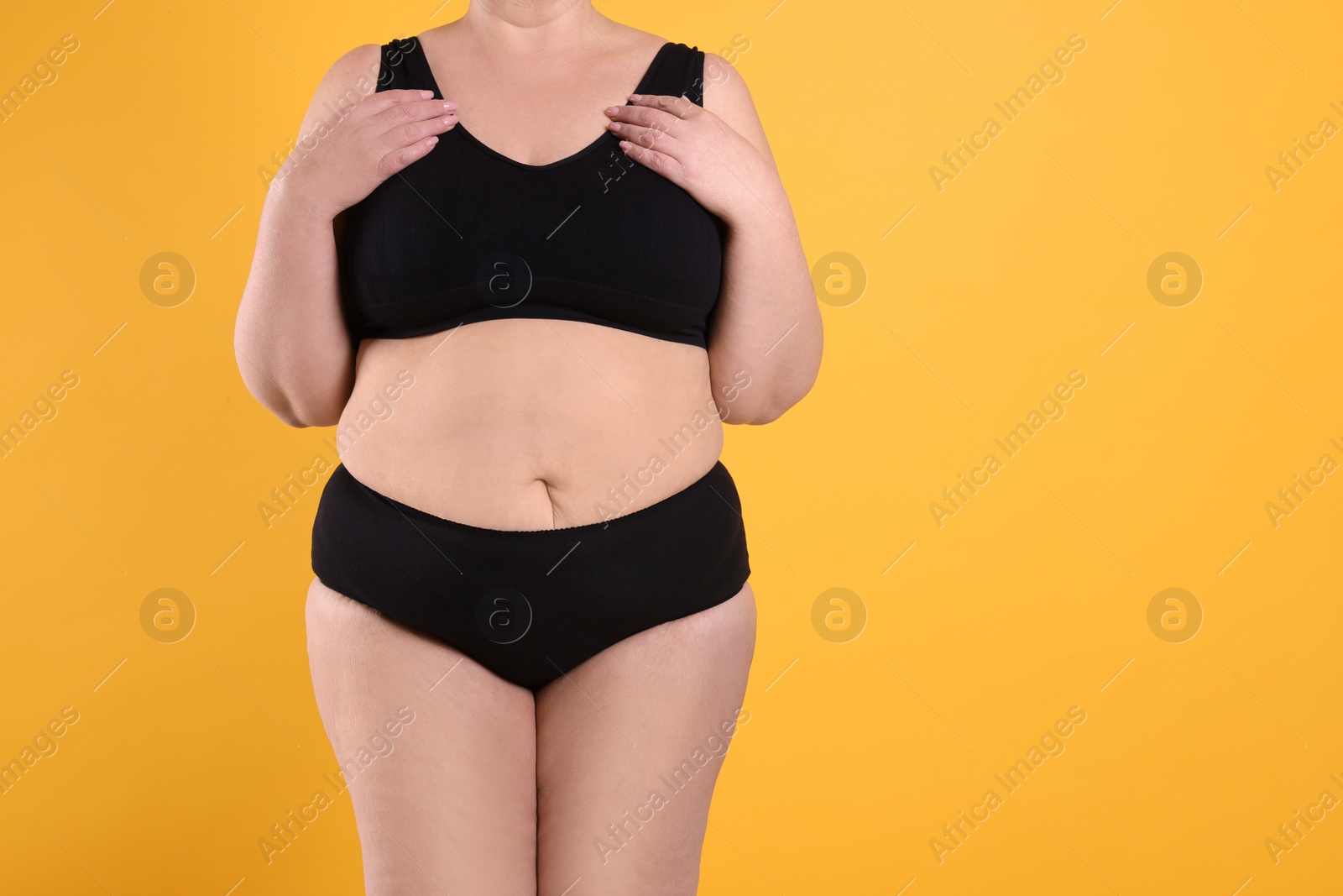 Photo of Overweight woman in underwear on orange background, closeup. Space for text