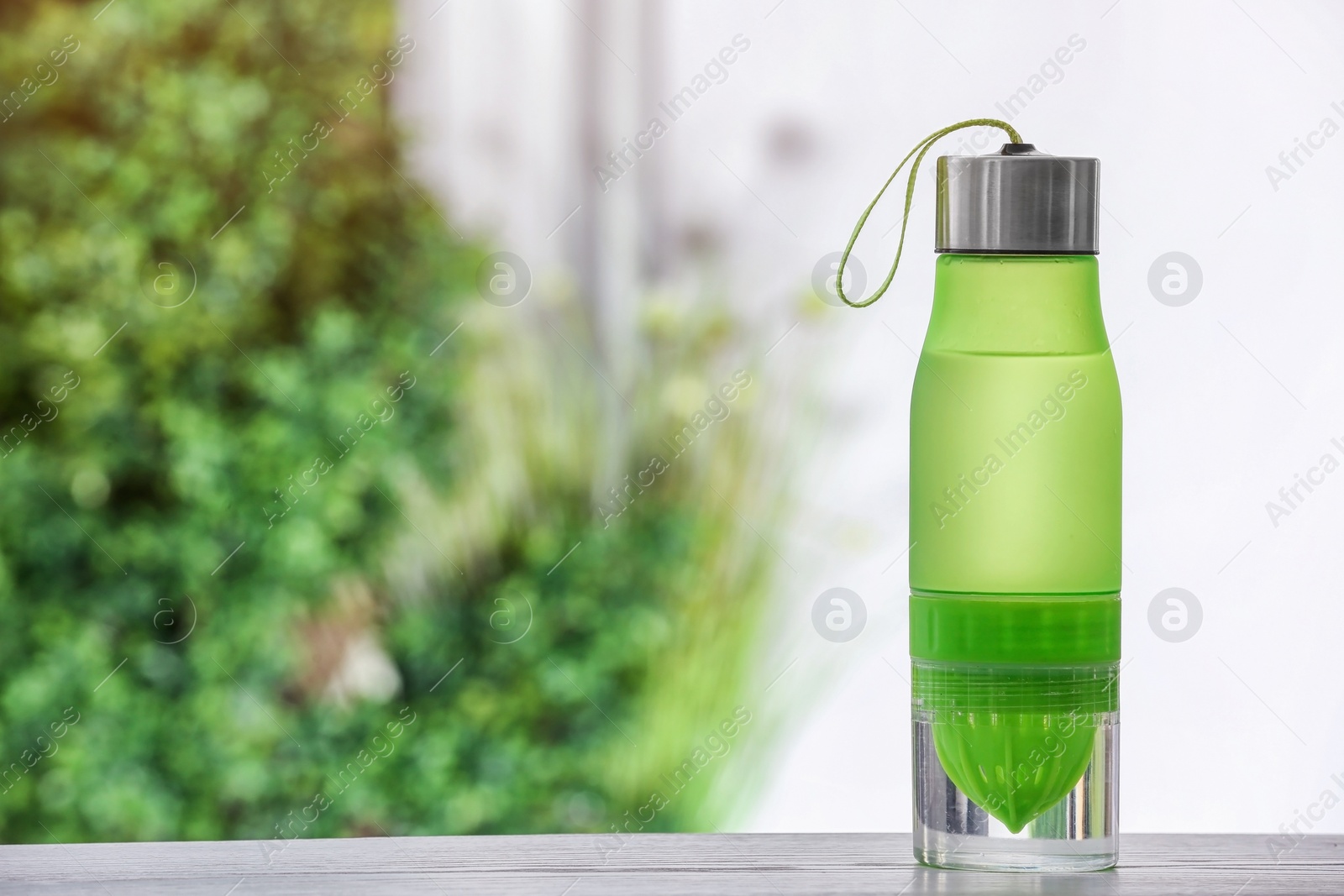 Photo of Sports water bottle on table against blurred background. Space for text