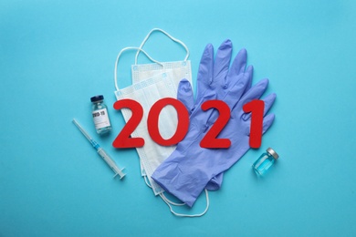 Photo of Flat lay composition with coronavirus vaccine and number 2021 on light blue background