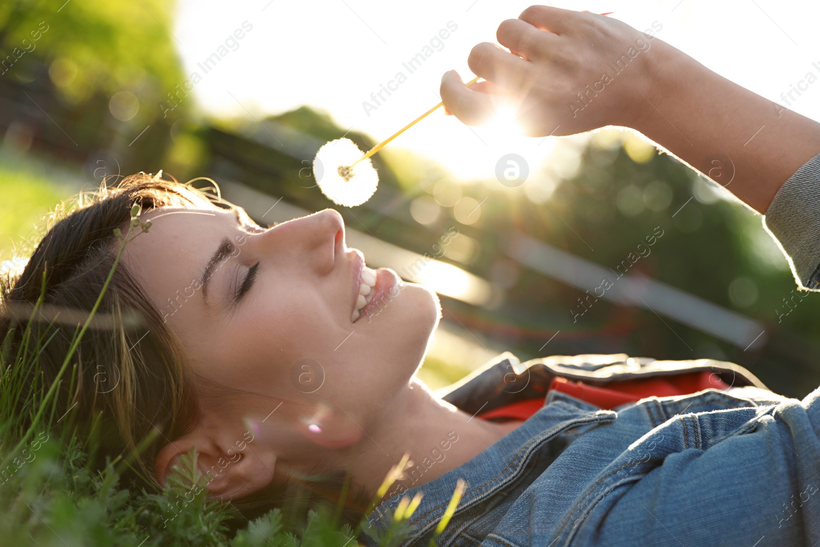 Photo of Young woman with dandelion in park on sunny day. Allergy free concept