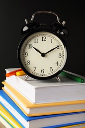 Photo of Alarm clock on stacked book near blackboard. School time