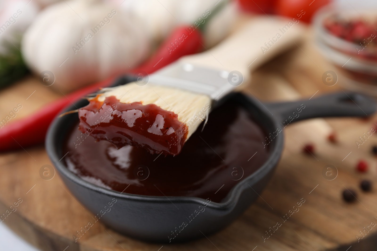 Photo of Marinade in gravy boat and basting brush on table, closeup