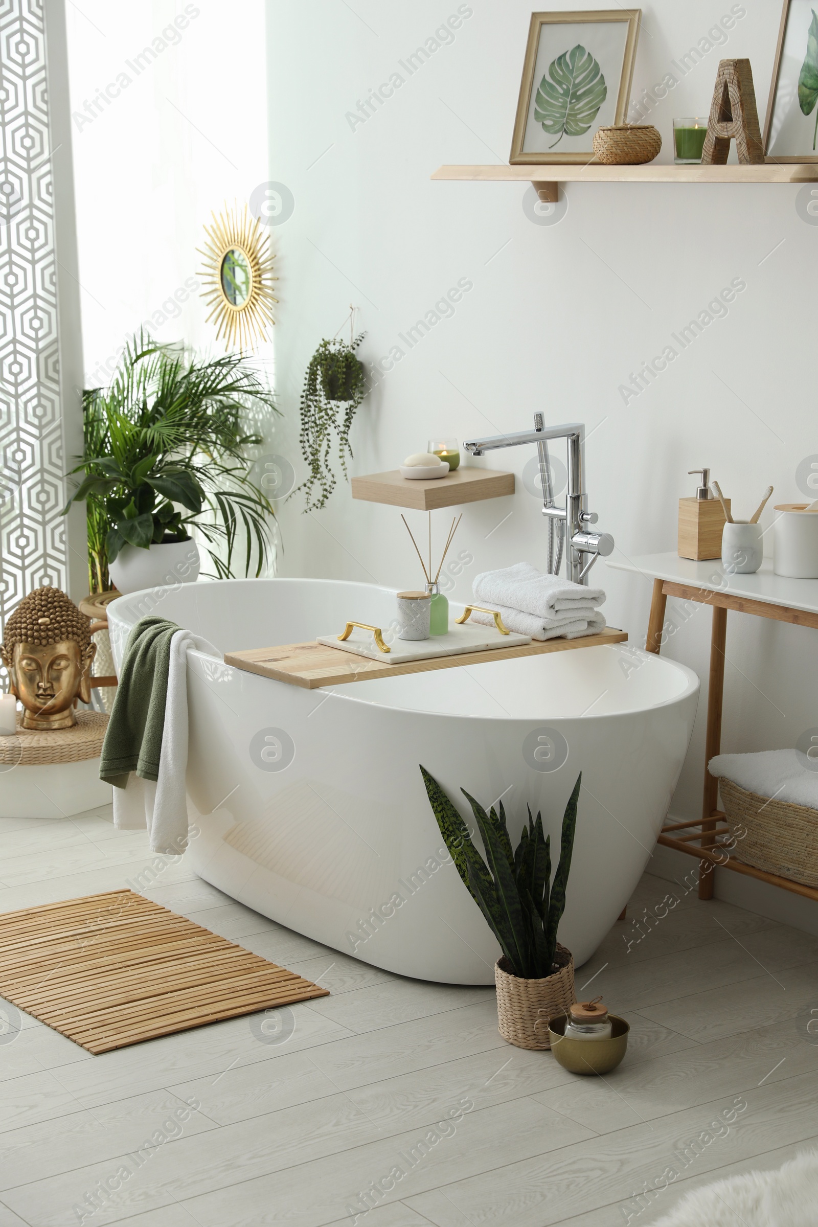 Photo of Stylish bathroom interior with modern tub, houseplants and beautiful decor. Home design