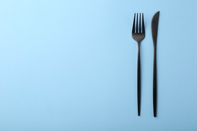 Photo of Stylish cutlery on light blue table, top view. Space for text