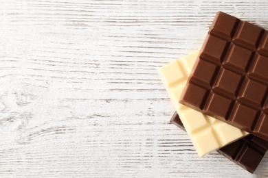 Photo of Different chocolate bars on wooden background, top view