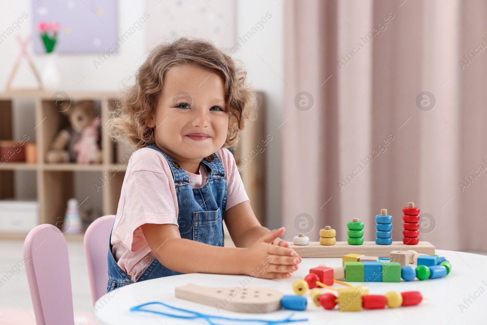 Photo of Motor skills development. Little girl playing with toys at table indoors