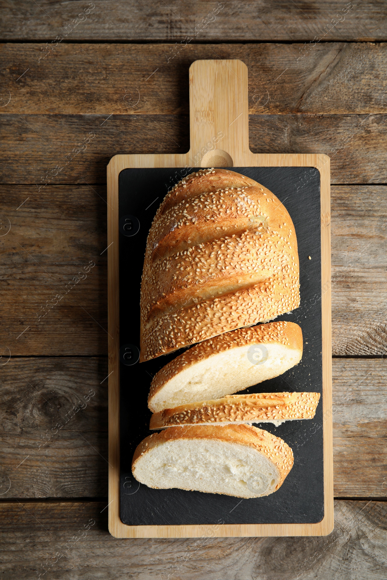 Photo of Board with tasty bread on wooden background, top view