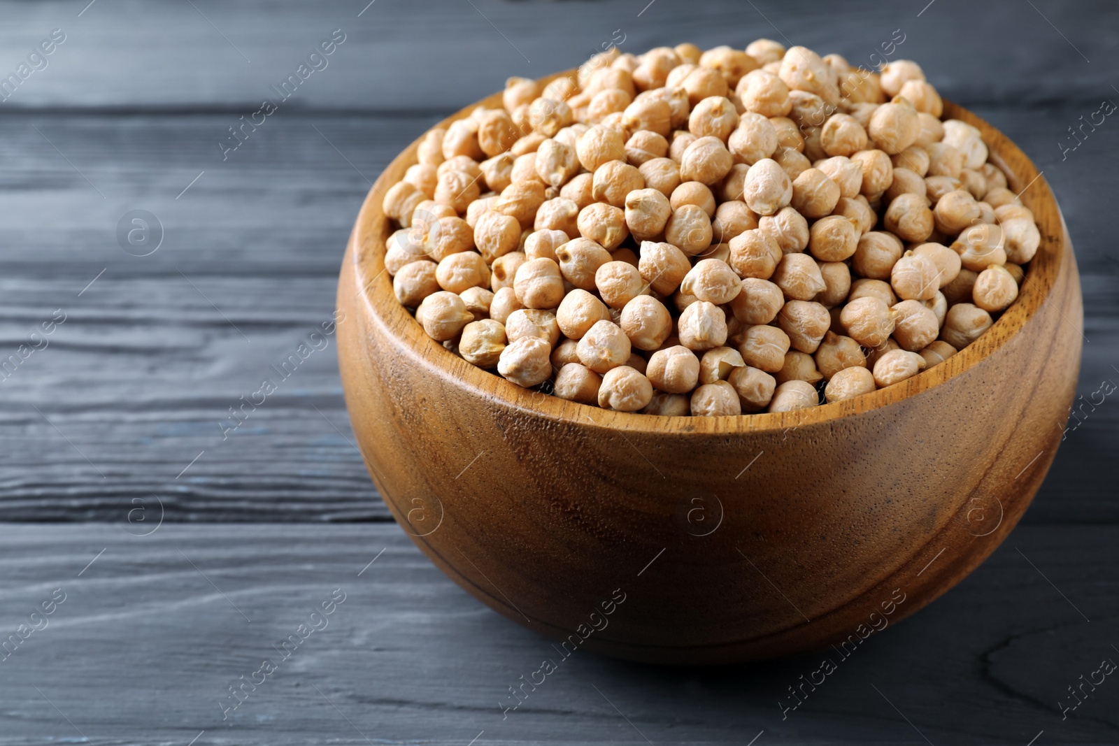 Photo of Raw chickpeas on black wooden table, closeup