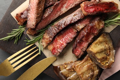 Photo of Delicious grilled beef with eggplant and rosemary served on table, top view