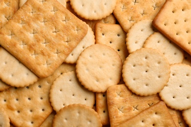 Many delicious crackers as background, top view