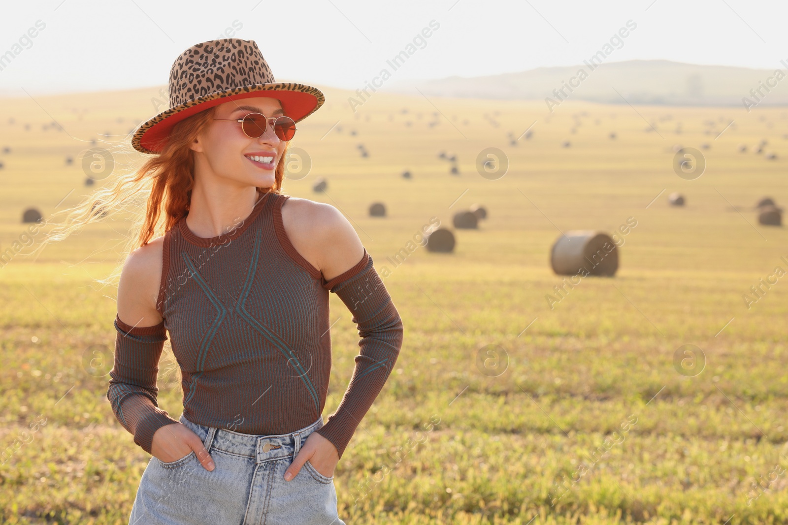 Photo of Beautiful happy hippie woman in hat in field, space for text