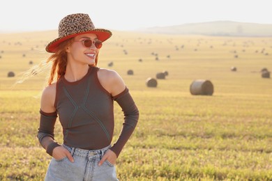 Beautiful happy hippie woman in hat in field, space for text
