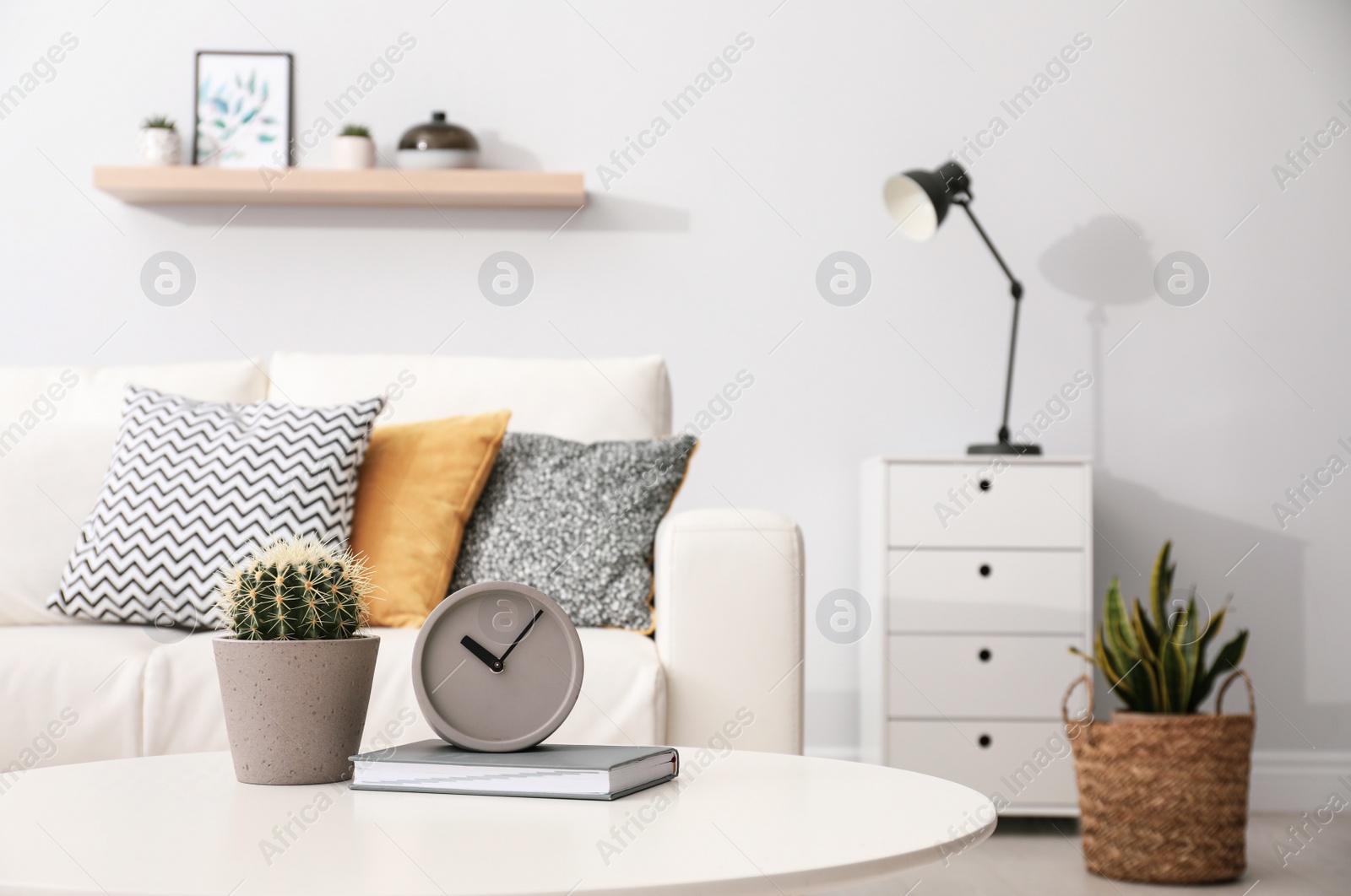 Photo of Clock and cactus on white table in stylish living room