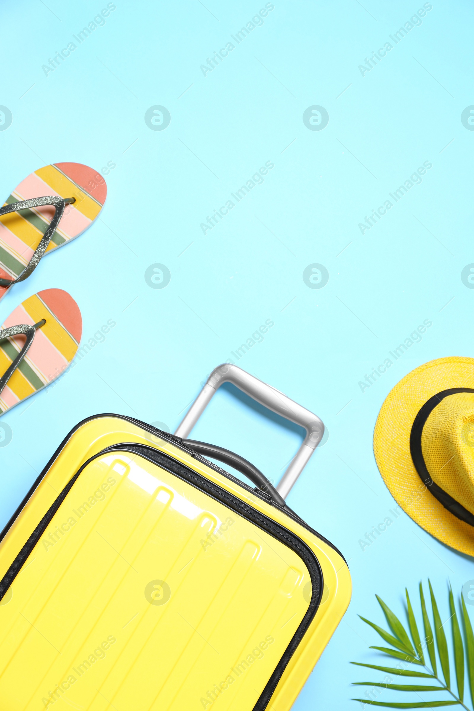 Photo of Suitcase and beach accessories on light blue background, flat lay. Space for text