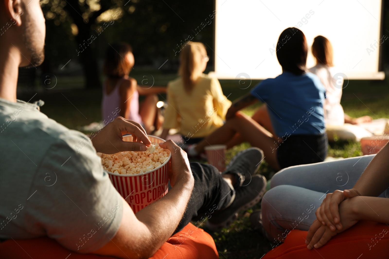 Photo of Young people with popcorn watching movie in open air cinema, closeup. Space for text