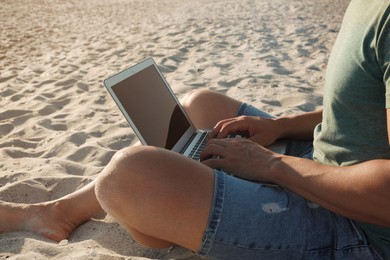 Photo of Man working with laptop on beach, closeup