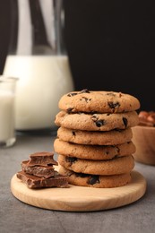 Stack of delicious chocolate chip cookies and milk on grey table