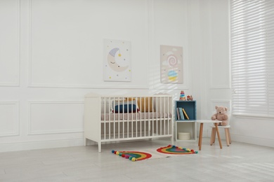 Photo of Cute baby room interior with comfortable crib and pictures
