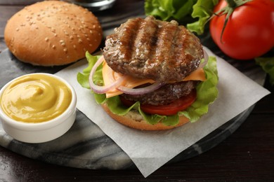 Photo of Tasty hamburger with patties, cheese and vegetables served on wooden table