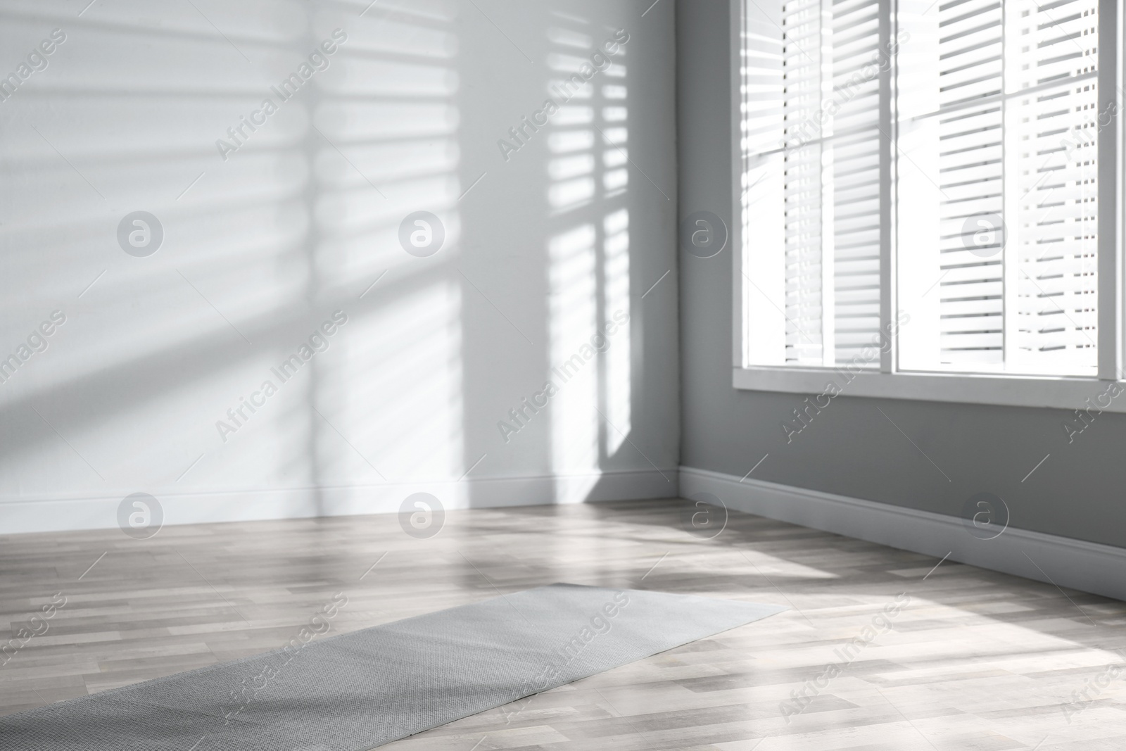 Photo of Unrolled grey yoga mat on floor in room
