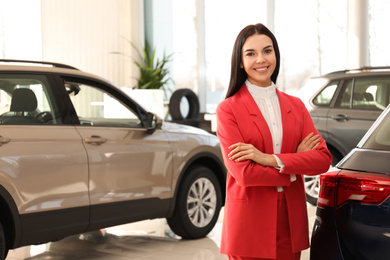 Photo of Happy young saleswoman in modern car salon