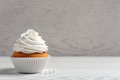 Delicious cupcake with cream on white wooden table. Space for text