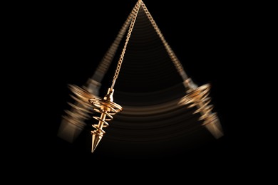 Image of Hypnosis session. Pendant swinging on black background, motion effect