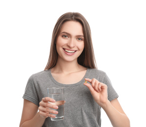 Young woman with vitamin pill and glass of water on white background