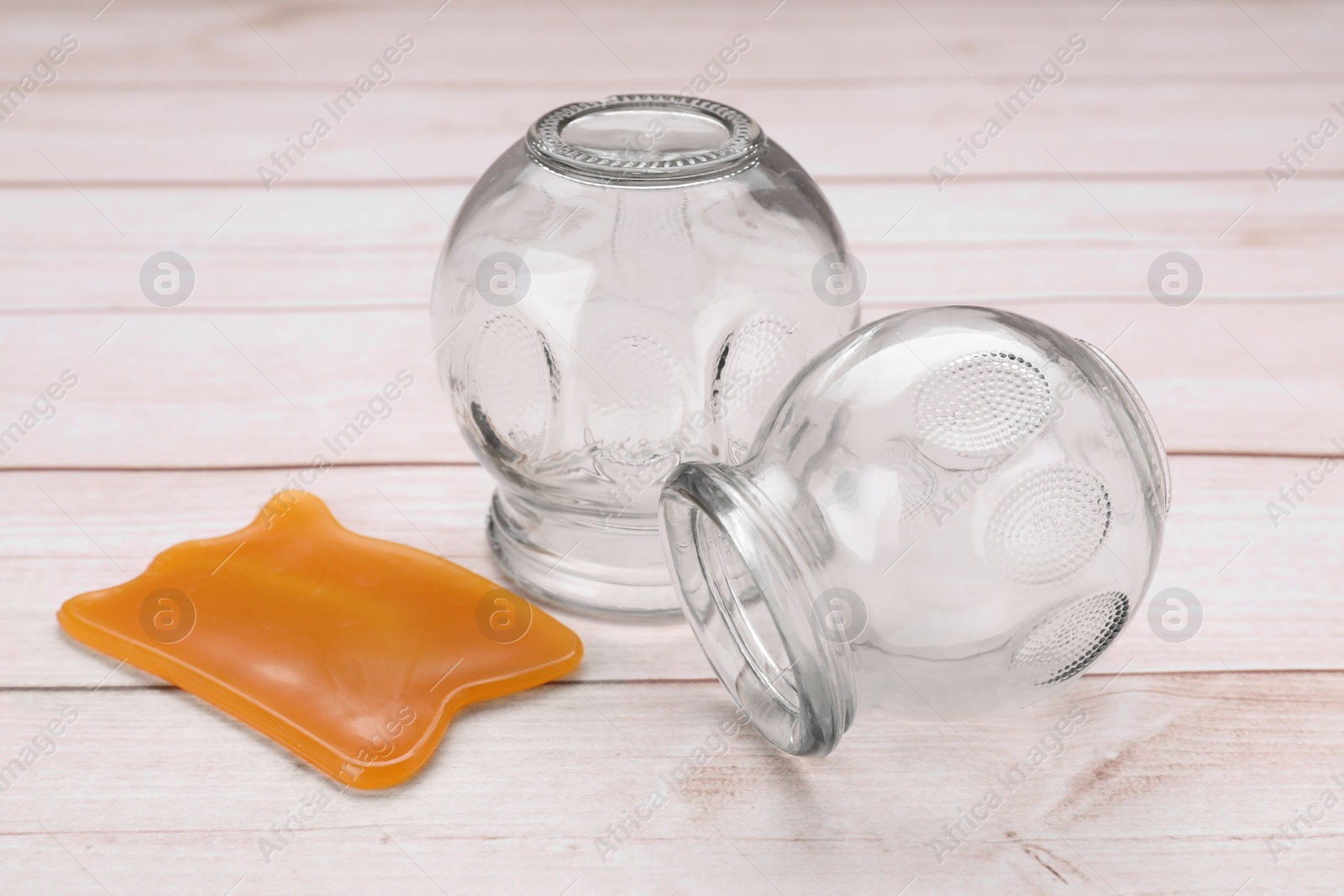 Photo of Glass cups and gua sha on white wooden table, closeup. Cupping therapy