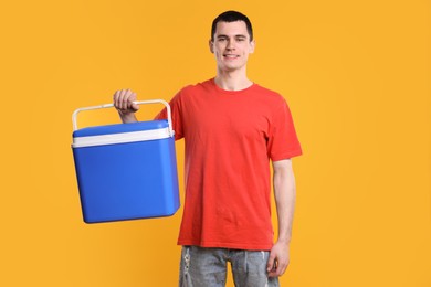 Man with blue cool box on orange background