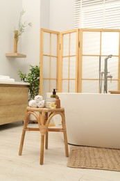 Different spa products on wicker table near ceramic tub in bathroom