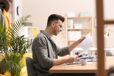 Journalist with papers at workplace in office