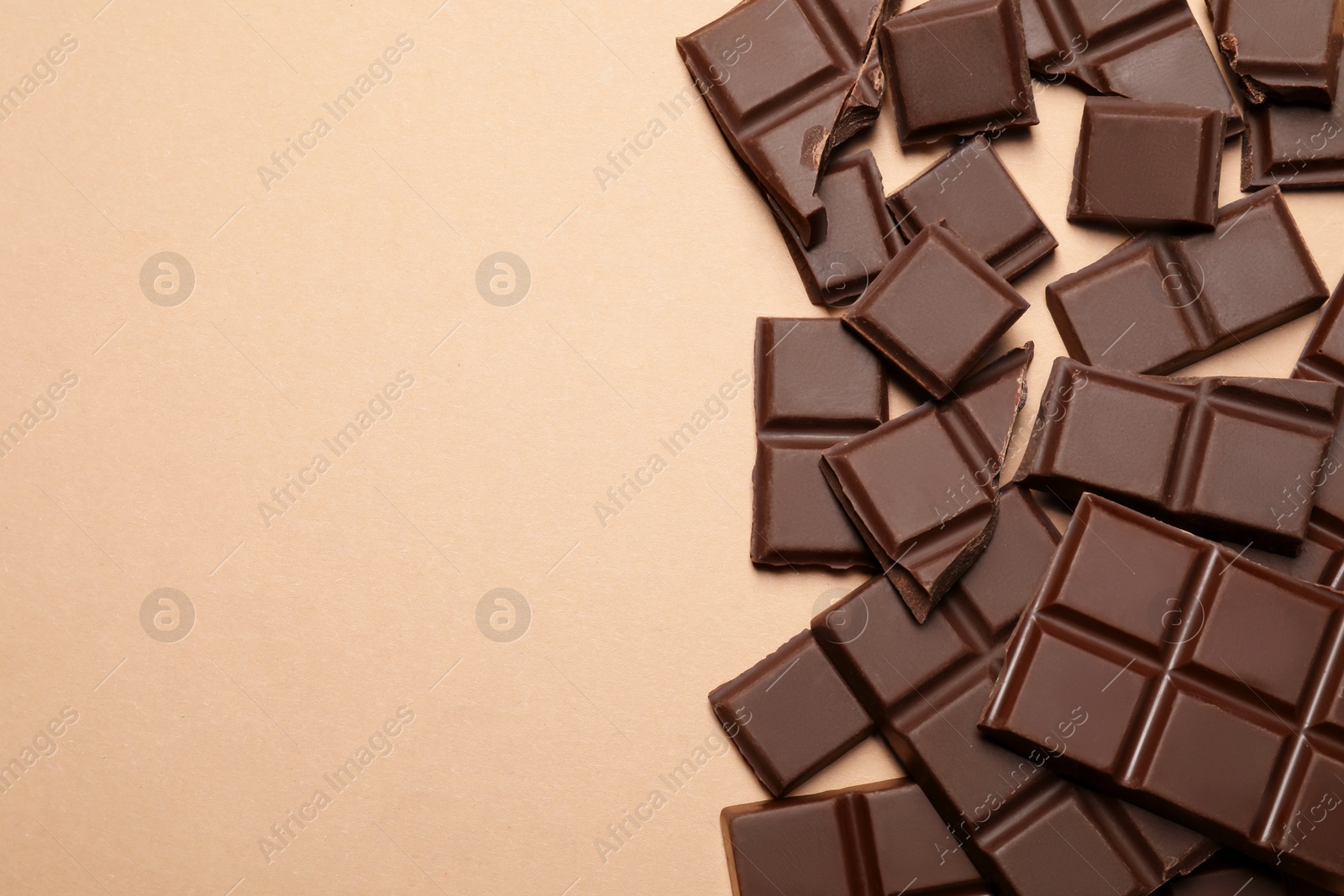 Photo of Pieces of delicious chocolate bars on beige background, flat lay. Space for text