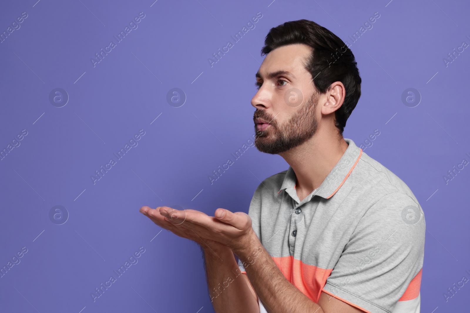 Photo of Handsome man blowing kiss on violet background. Space for text