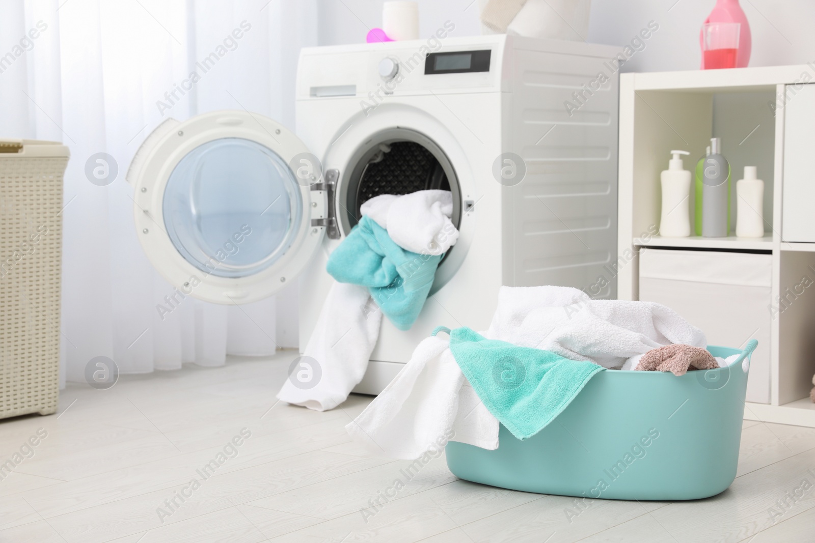 Photo of Bathroom interior with dirty towels in basket and washing machine