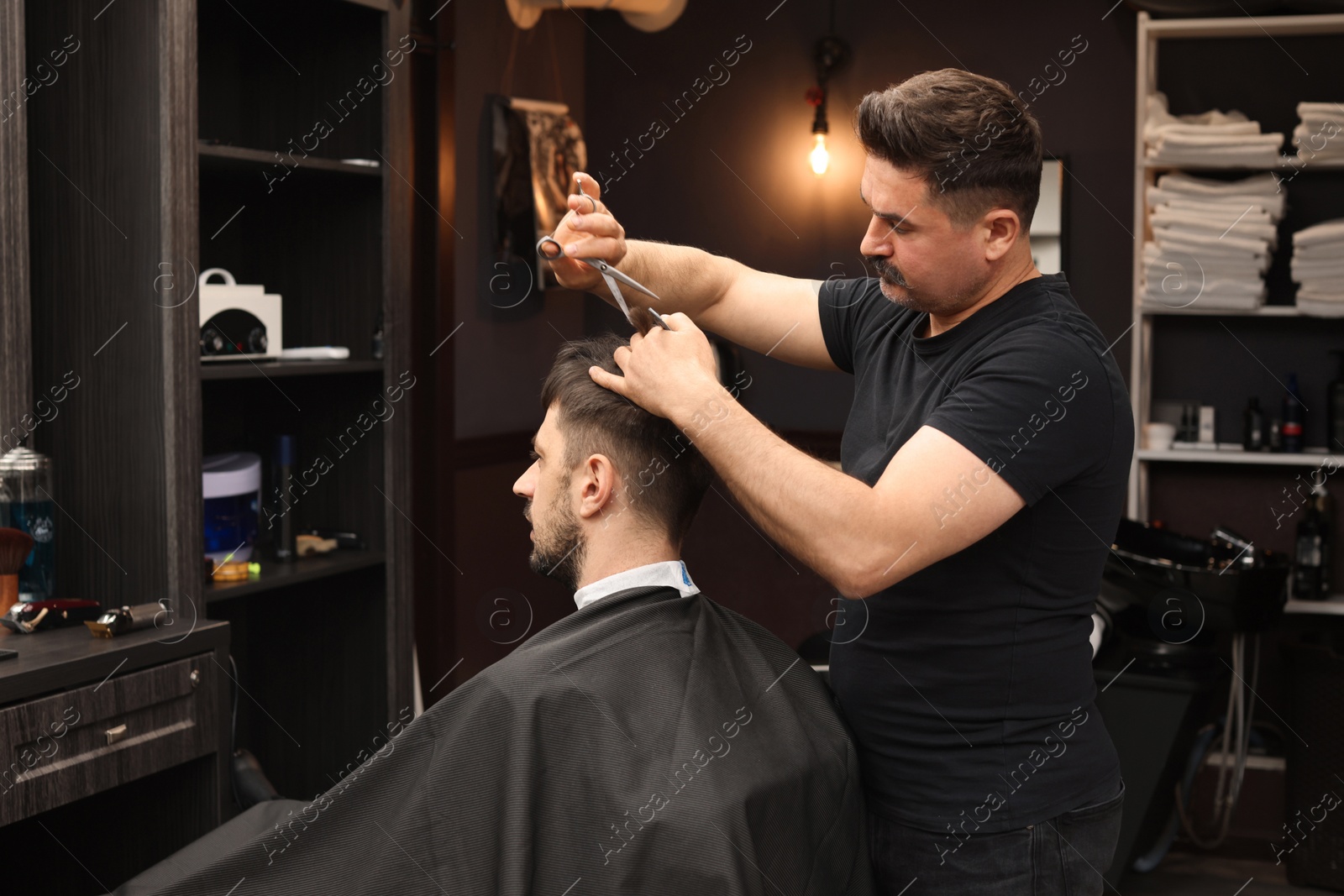 Photo of Professional hairdresser cutting man's hair in barbershop