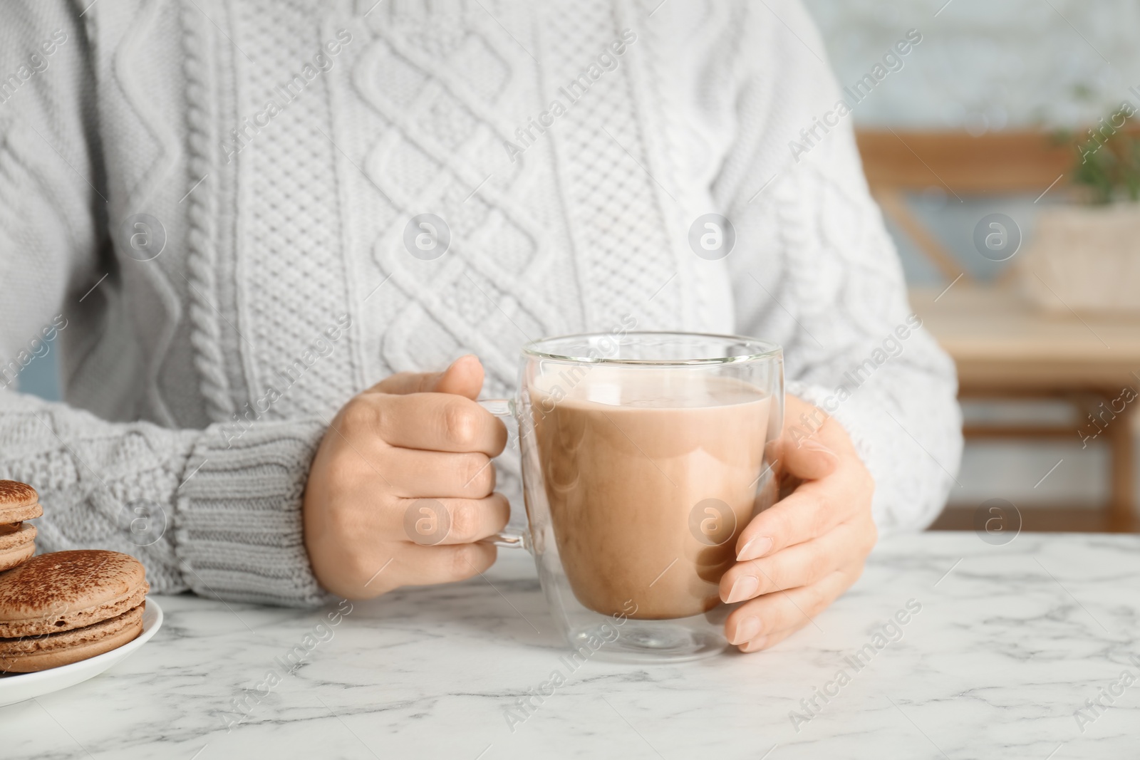 Photo of Young woman with delicious hot cocoa drink at table