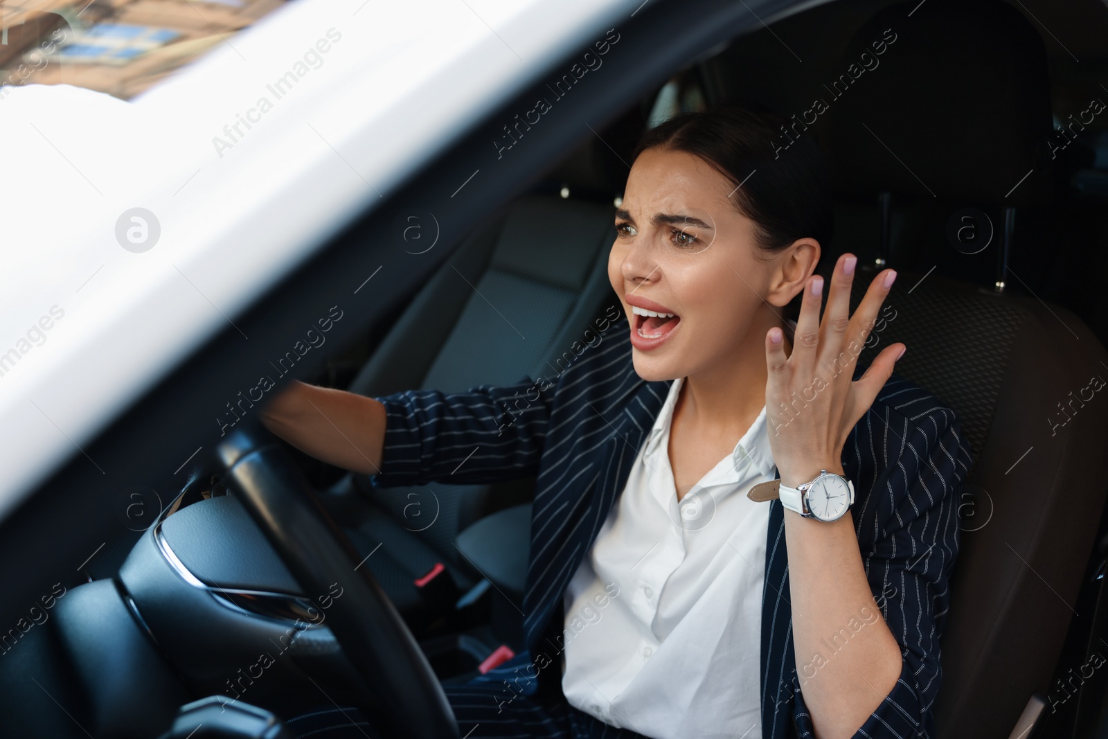 Photo of Angry driver screaming in her car. Stuck in traffic jam